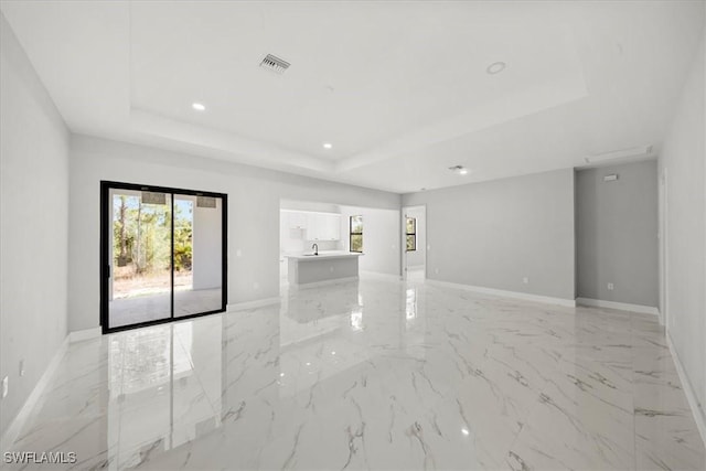 203 E 10th St, Lehigh Acres, FL 33972 - spare room with a tray ceiling, baseboards, light marble finish floors, and recessed lighting