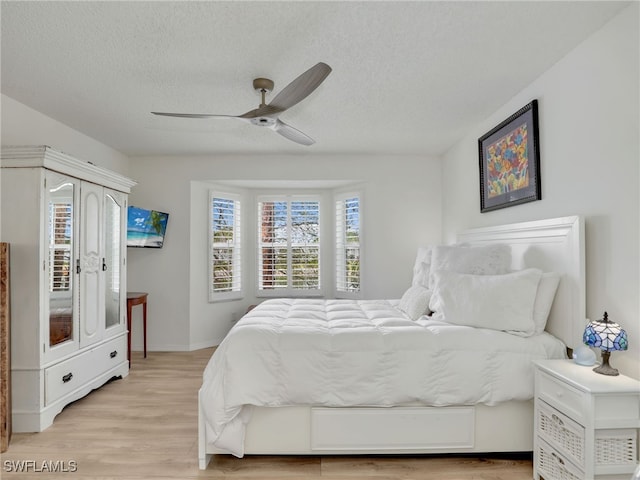 935 New Waterford Dr Unit F204, Naples, FL 34104 - bedroom featuring a ceiling fan, baseboards, light wood-style flooring, and a textured ceiling