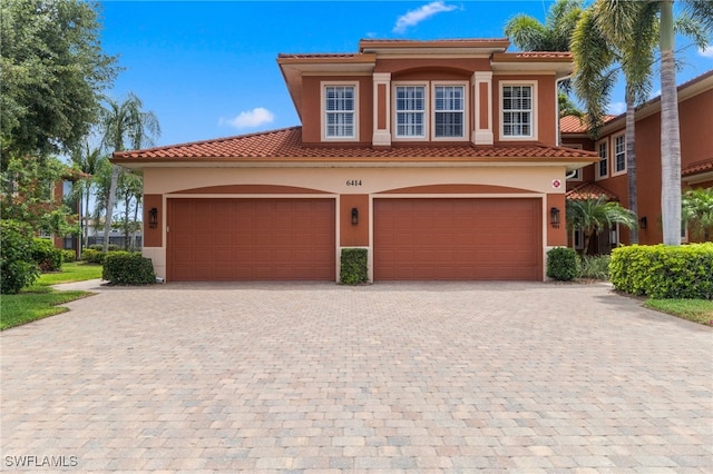 mediterranean / spanish-style house featuring driveway, stucco siding, and a tile roof