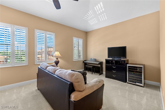 living room with light colored carpet, baseboards, ceiling fan, and beverage cooler