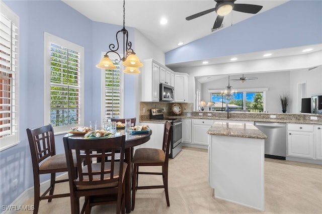 kitchen with a peninsula, a center island, ceiling fan with notable chandelier, white cabinets, and appliances with stainless steel finishes