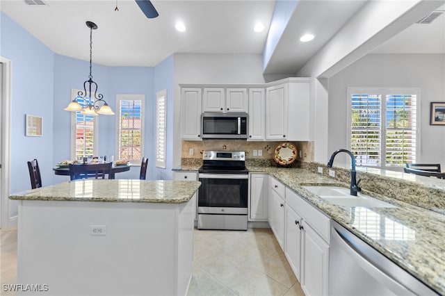 kitchen featuring a sink, decorative backsplash, a kitchen island, stainless steel appliances, and white cabinets