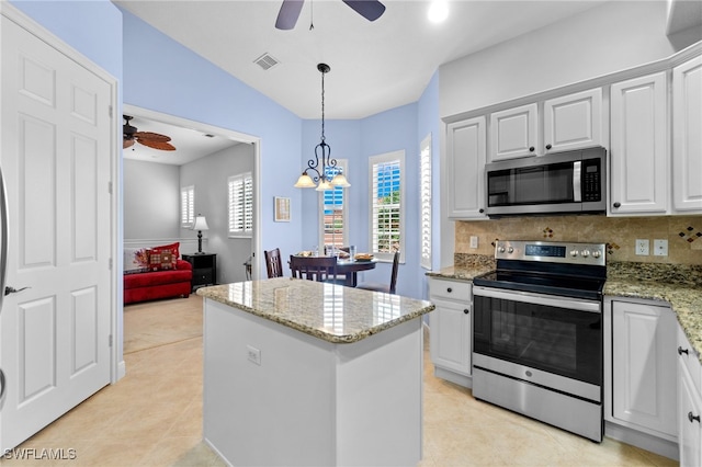 kitchen with appliances with stainless steel finishes, a center island, ceiling fan with notable chandelier, and a healthy amount of sunlight