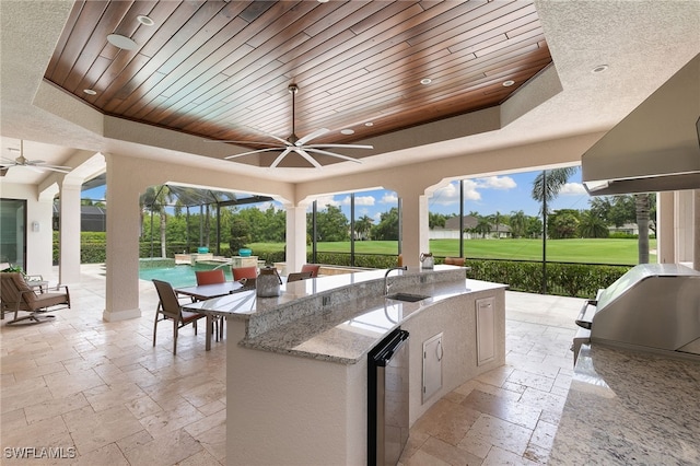 view of patio / terrace featuring outdoor wet bar, area for grilling, ceiling fan, a lanai, and an outdoor pool