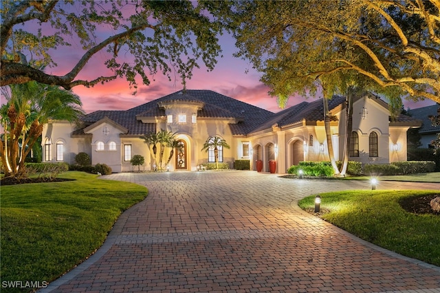mediterranean / spanish-style home featuring curved driveway, stucco siding, and a front yard