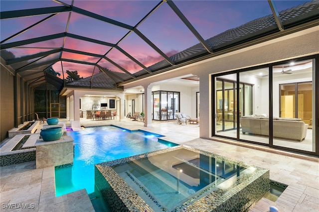 pool at dusk featuring outdoor dining area, a pool with connected hot tub, and a patio area