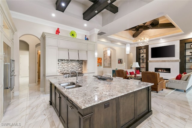 kitchen featuring coffered ceiling, marble finish floor, ornamental molding, a lit fireplace, and arched walkways