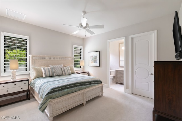 bedroom featuring ceiling fan, visible vents, baseboards, ensuite bathroom, and light carpet