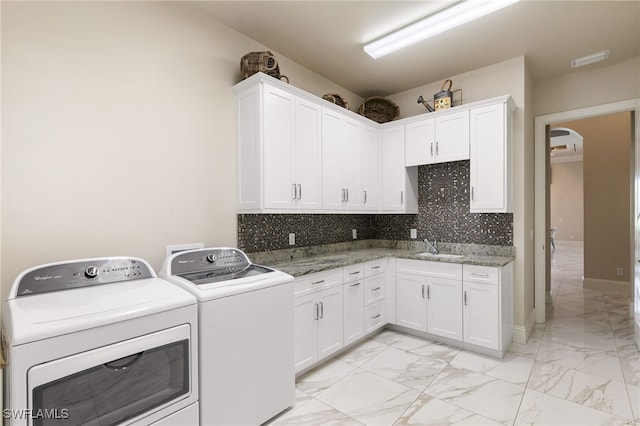 clothes washing area featuring a sink, cabinet space, washing machine and clothes dryer, arched walkways, and marble finish floor