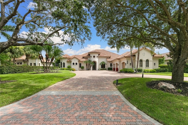 mediterranean / spanish home featuring a front lawn, a tiled roof, stucco siding, and curved driveway