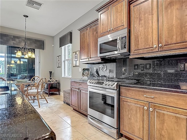 10843 Valentina Ct, Fort Myers, FL 33913 - kitchen with stainless steel appliances, decorative backsplash, a chandelier, dark stone counters, and hanging light fixtures