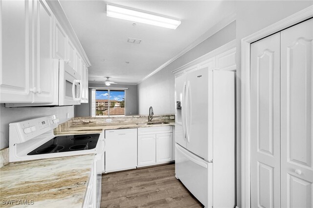 kitchen featuring white appliances, a sink, white cabinets, wood finished floors, and ornamental molding