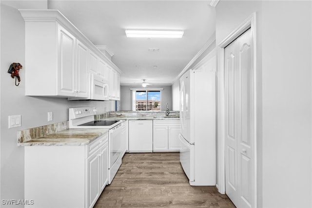 kitchen with white appliances, a sink, light wood finished floors, white cabinetry, and ceiling fan