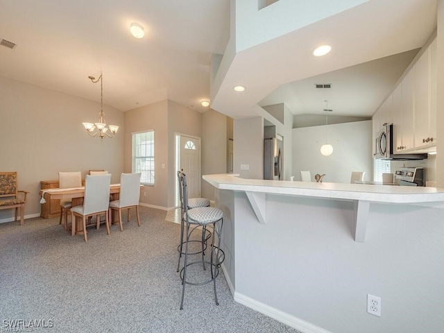 kitchen featuring appliances with stainless steel finishes, white cabinetry, a breakfast bar, light carpet, and light countertops