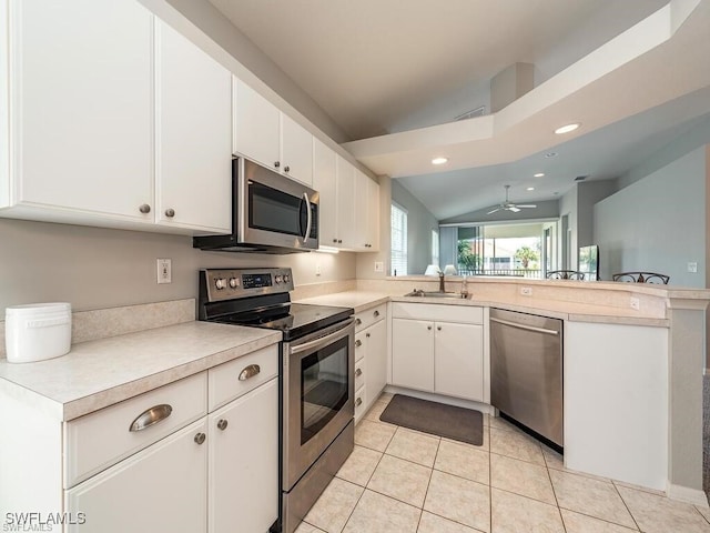 kitchen with appliances with stainless steel finishes, a sink, a peninsula, recessed lighting, and light countertops