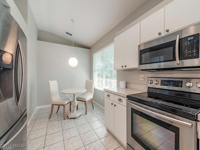 kitchen with appliances with stainless steel finishes, vaulted ceiling, light countertops, white cabinetry, and decorative light fixtures