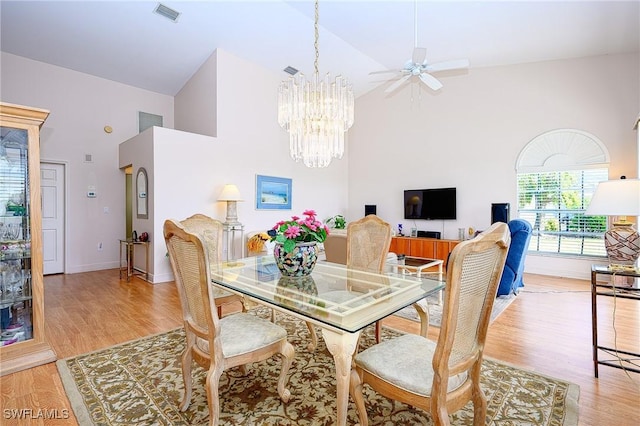 dining space with high vaulted ceiling, a chandelier, light wood-type flooring, baseboards, and a ceiling fan