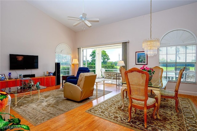 dining area featuring healthy amount of natural light, wood finished floors, a chandelier, a ceiling fan, and high vaulted ceiling