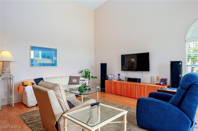 living area with light wood-style floors and a towering ceiling