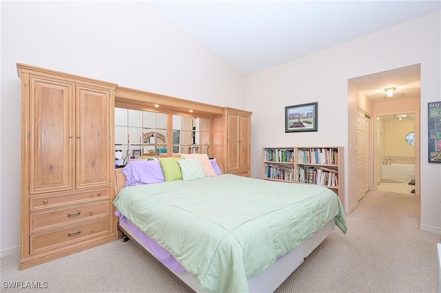 bedroom with light colored carpet, high vaulted ceiling, baseboards, and ensuite bathroom