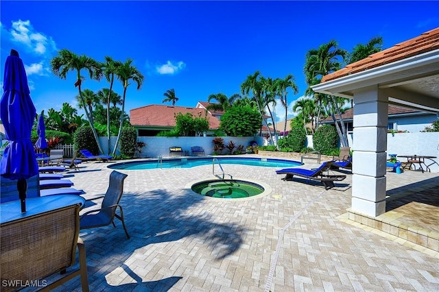 community pool with a hot tub, a fenced backyard, and a patio