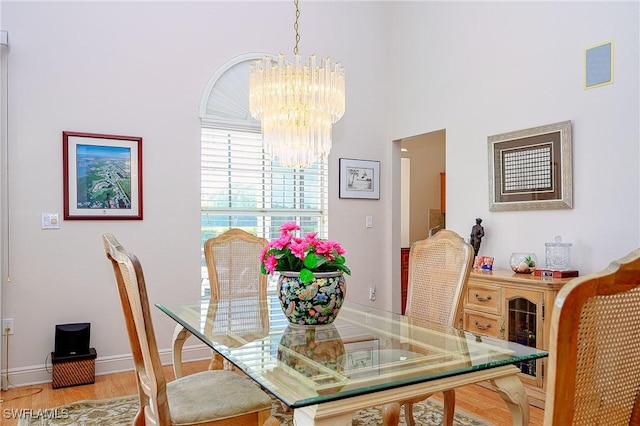 dining room featuring a chandelier, light wood finished floors, and baseboards