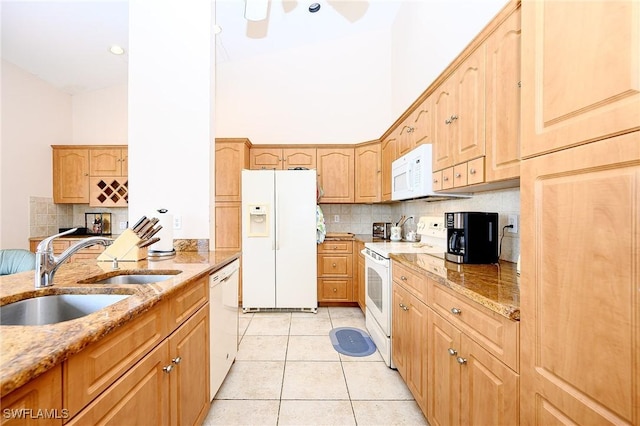 kitchen with white appliances, a sink, a high ceiling, tasteful backsplash, and light stone countertops