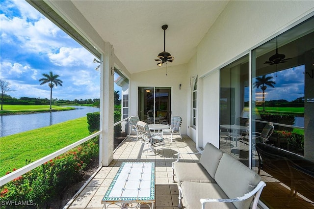 sunroom featuring a water view, a ceiling fan, vaulted ceiling, and an outdoor living space