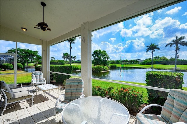 sunroom featuring a water view, tile patterned floors, a ceiling fan, and lofted ceiling