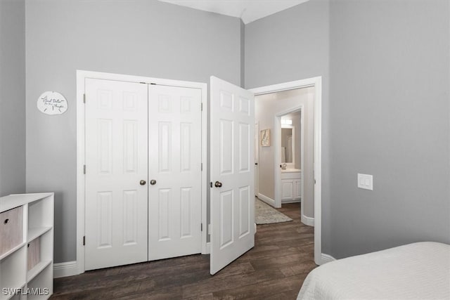 bedroom featuring dark wood-style flooring, baseboards, a sink, and a closet