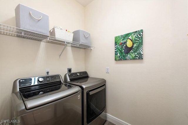 washroom with laundry area, baseboards, and washing machine and dryer