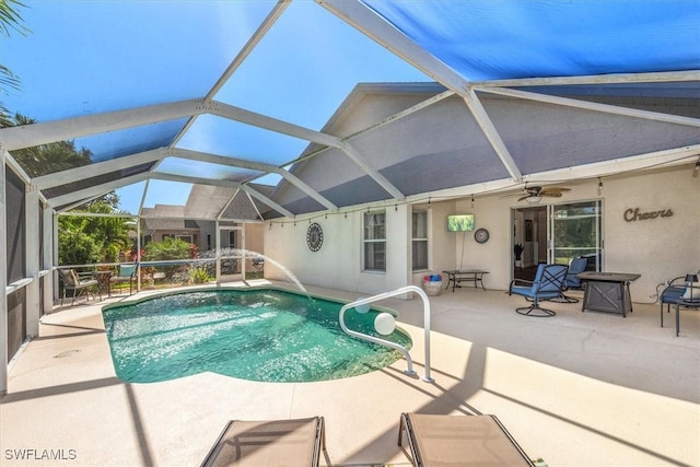 outdoor pool with glass enclosure, a ceiling fan, and a patio area