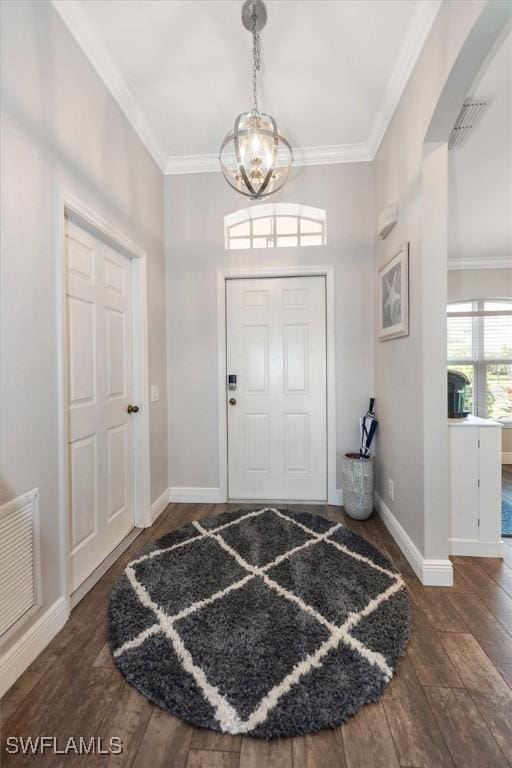 entrance foyer with crown molding, visible vents, an inviting chandelier, wood finished floors, and baseboards