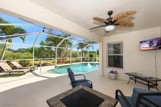 outdoor pool with glass enclosure, ceiling fan, and a patio area