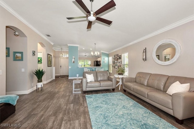 living room featuring dark wood-style flooring, arched walkways, baseboards, ceiling fan with notable chandelier, and ornamental molding