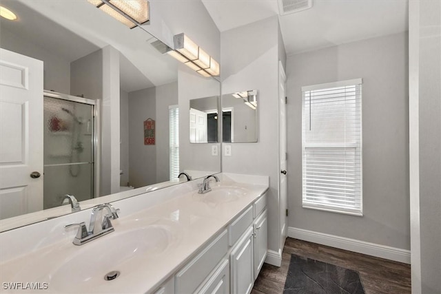 bathroom featuring visible vents, a sink, a stall shower, and wood finished floors
