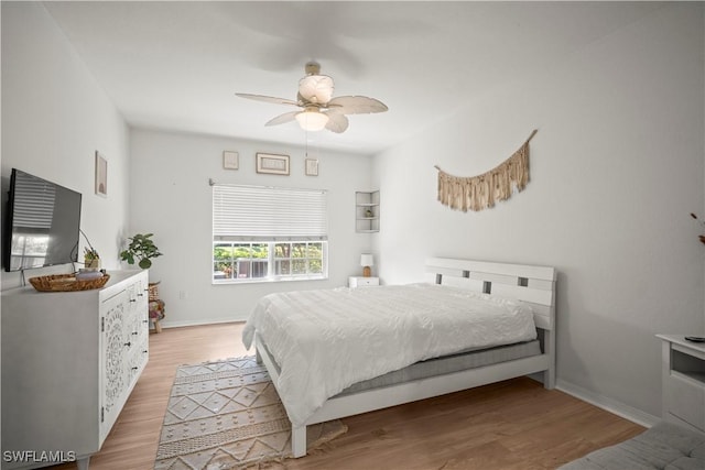bedroom featuring ceiling fan, baseboards, and light wood-style floors