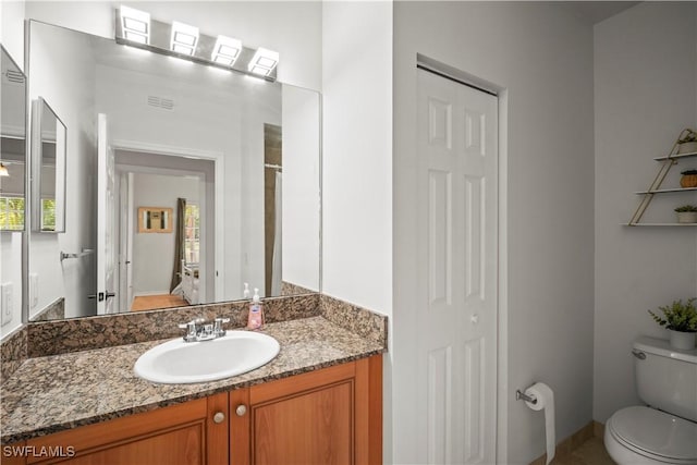 bathroom with vanity, toilet, a closet, and visible vents