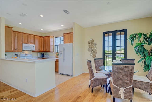 kitchen with white appliances, visible vents, and light wood-type flooring