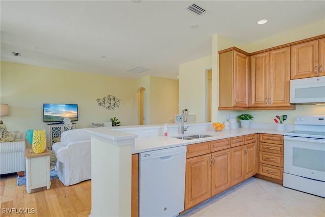kitchen featuring visible vents, a peninsula, white appliances, light countertops, and a sink