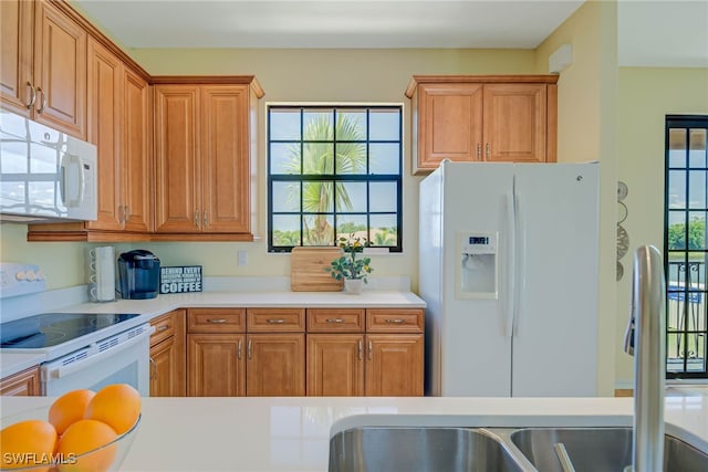 kitchen with light countertops, a sink, brown cabinets, and white appliances