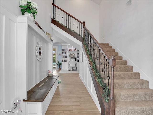 staircase with wood finished floors, a high ceiling, and visible vents