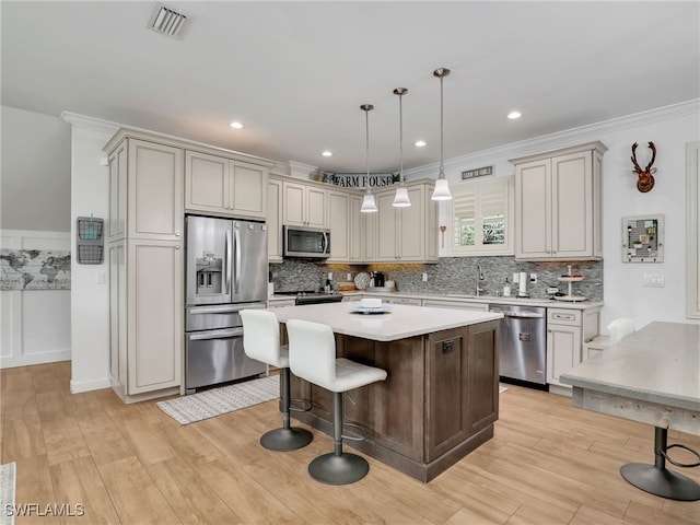 kitchen featuring light wood-style floors, light countertops, stainless steel appliances, visible vents, and ornamental molding