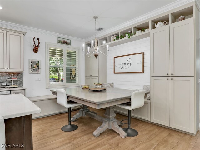 dining space featuring ornamental molding, light wood finished floors, a chandelier, and breakfast area