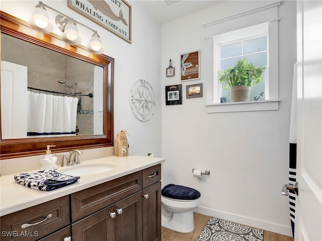 bathroom featuring vanity, toilet, baseboards, wood finished floors, and a shower with curtain
