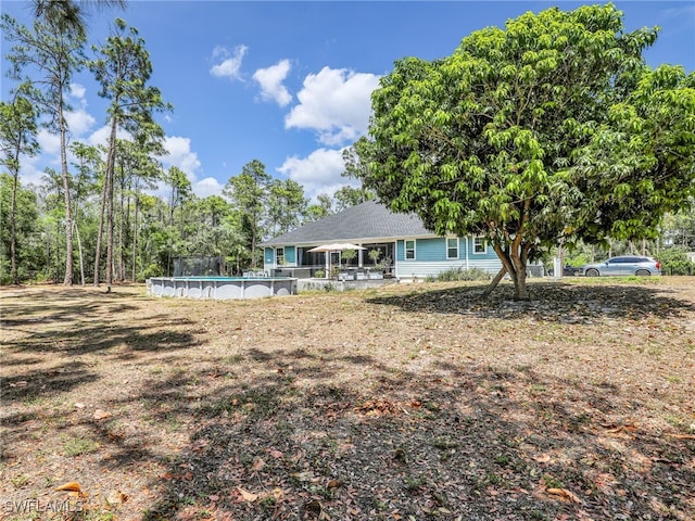 back of house with an outdoor pool and roof with shingles