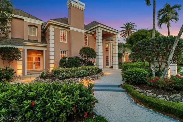 13488 Rosewood Ln, Naples, FL 34119 - view of front facade with stucco siding, a chimney, and french doors