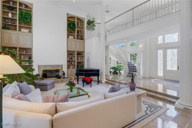 13488 Rosewood Ln, Naples, FL 34119 - living room featuring a towering ceiling, built in shelves, stairs, and a glass covered fireplace