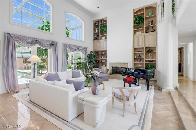 13488 Rosewood Ln, Naples, FL 34119 - living room with a towering ceiling, crown molding, built in shelves, baseboards, and a high end fireplace