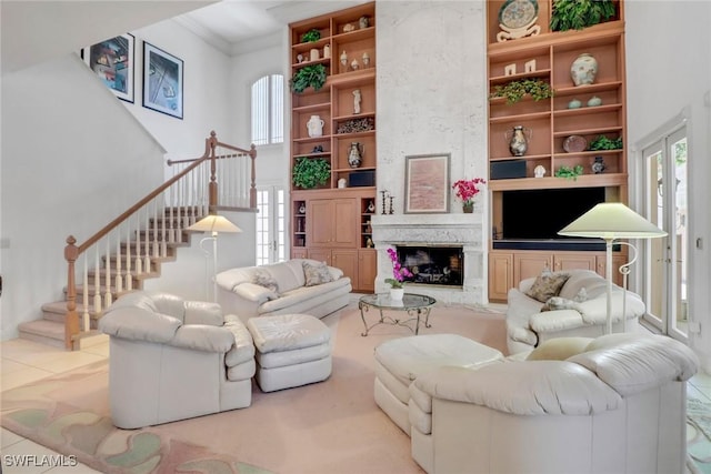 13488 Rosewood Ln, Naples, FL 34119 - living room featuring stairway, a towering ceiling, ornamental molding, french doors, and a large fireplace